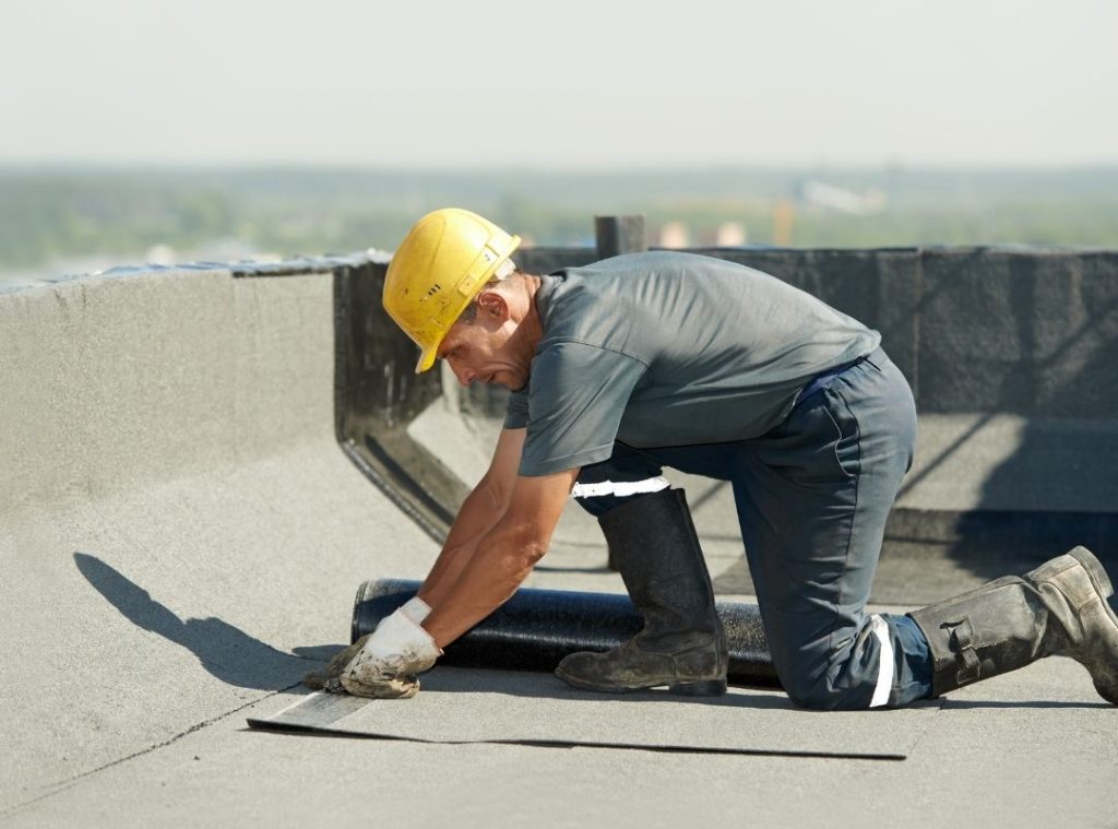 Worker finishing the edge detail on a flat roof