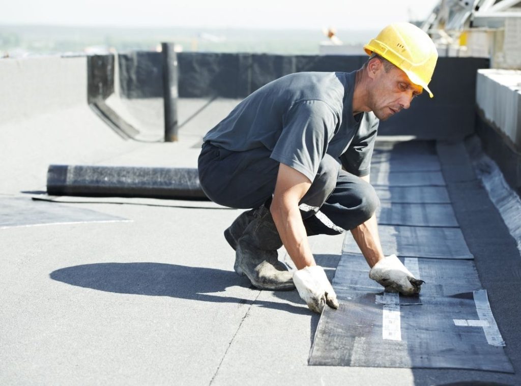 Worker installing membrane on a flat commercial roof