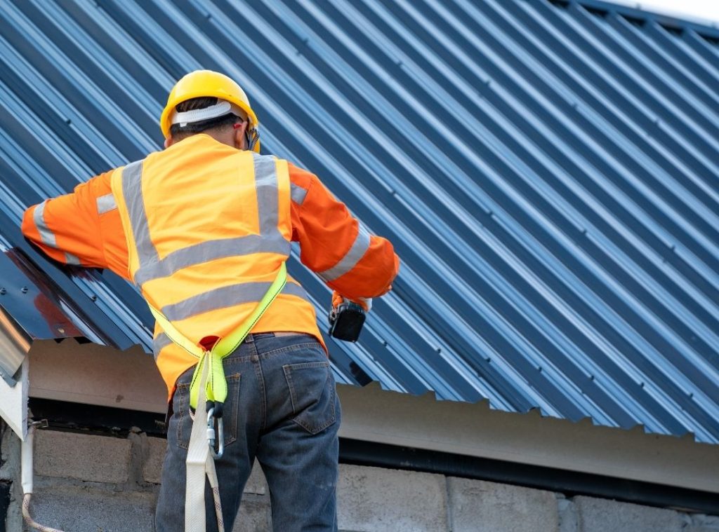 Roofer working along the edge of a blue corrugated metal roof