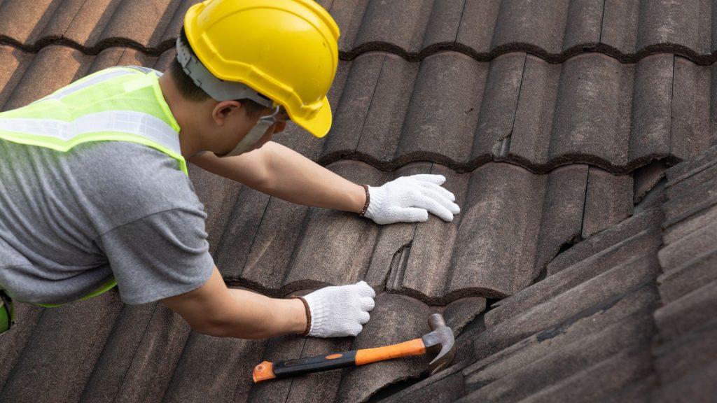Worker fitting roof tiles by hand