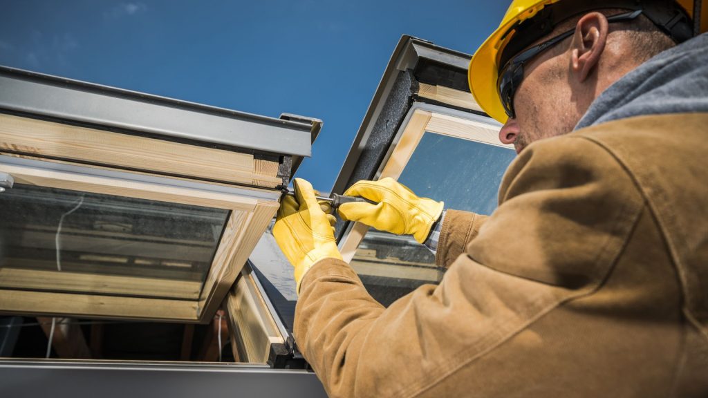 Worker fitting a skylight into a roof