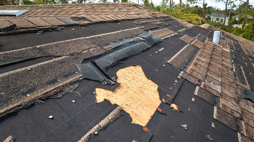 Storm damaged shingles with the decking exposed underneath