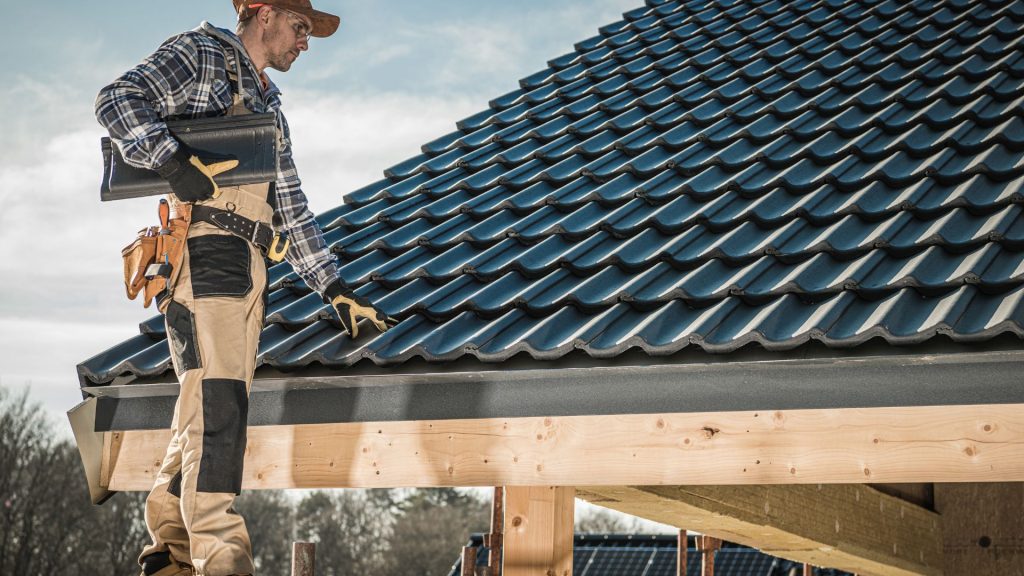 Roofer working on new timber framing beside a tiled roof