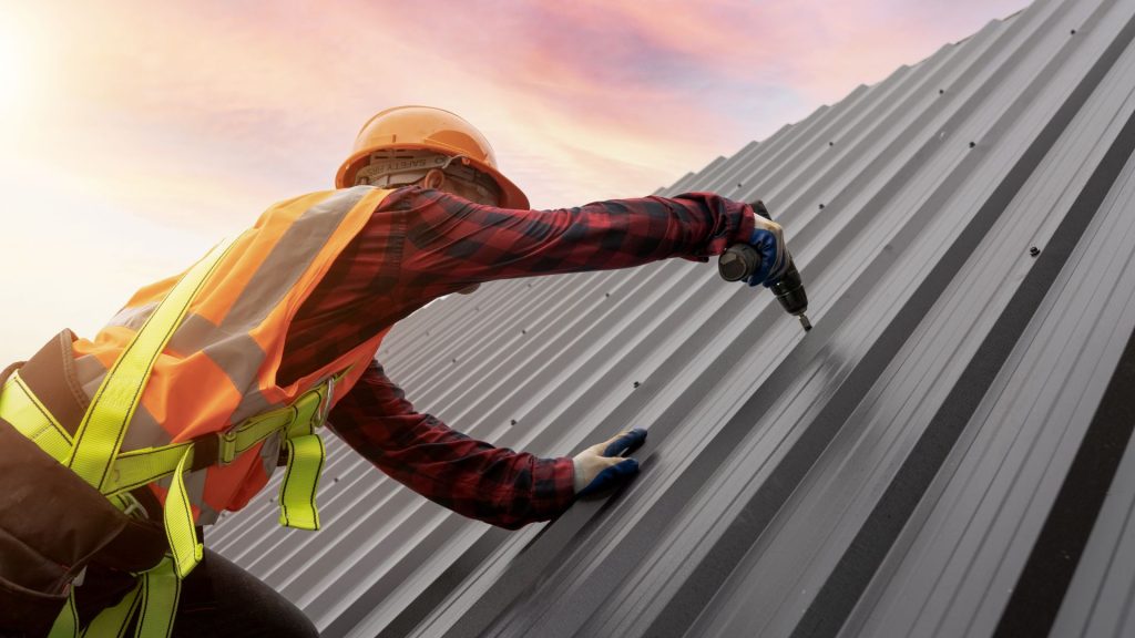 Roofer working on a metal roof at sunset
