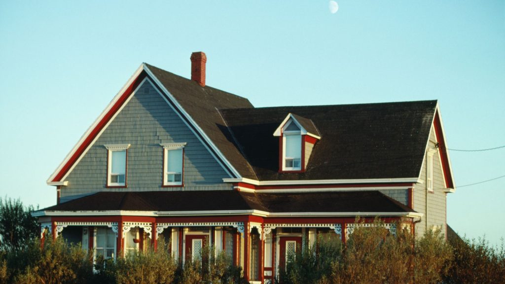 Victorian style home with a dark roof at sunset