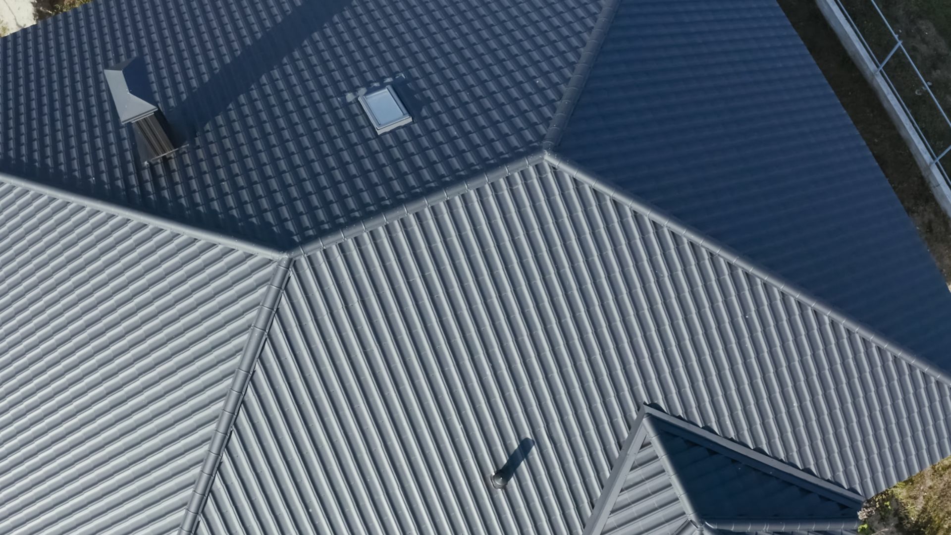 Dark corrugated metal roof planes against a blue sky