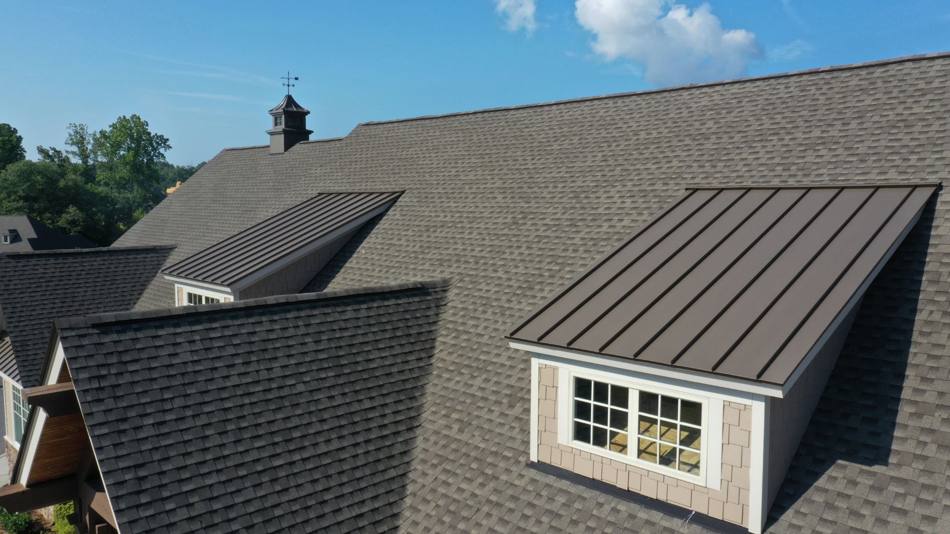 Home with gray shingles and a brown metal roof section