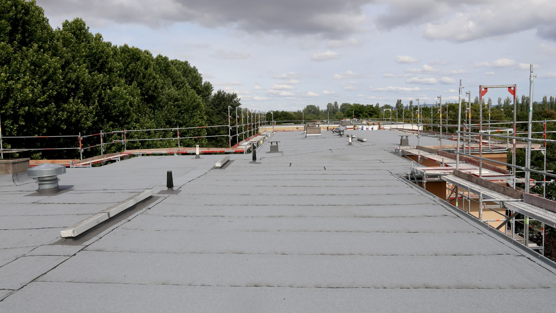 Large flat commercial roof under a cloudy sky