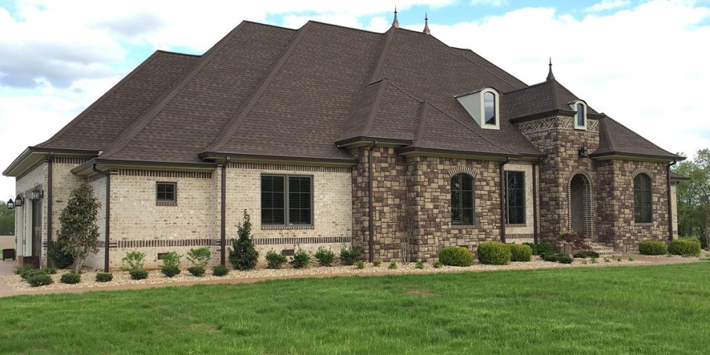 Large stone and brick home with a dark roof