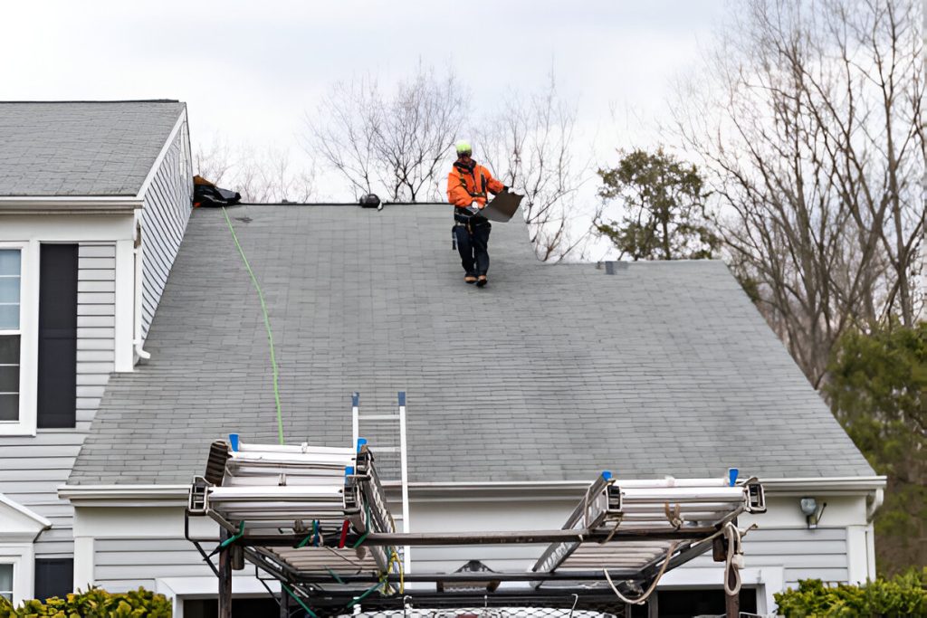 Worker on a house roof with a lift alongside